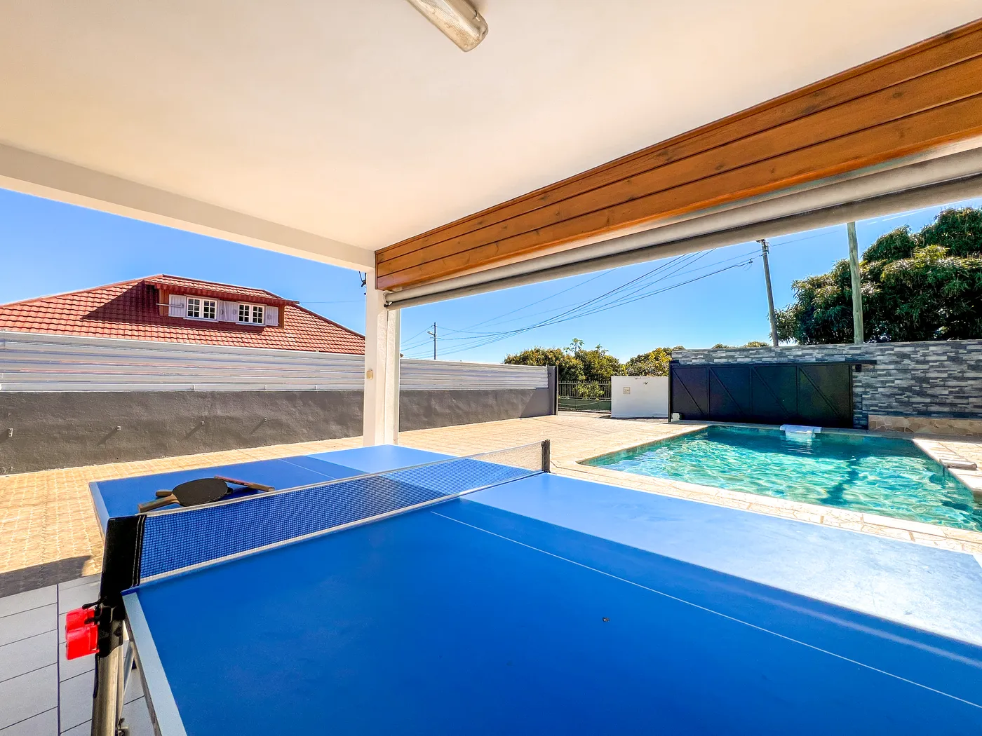 Table de ping-pong ouverte sur la piscine et le ciel bleu